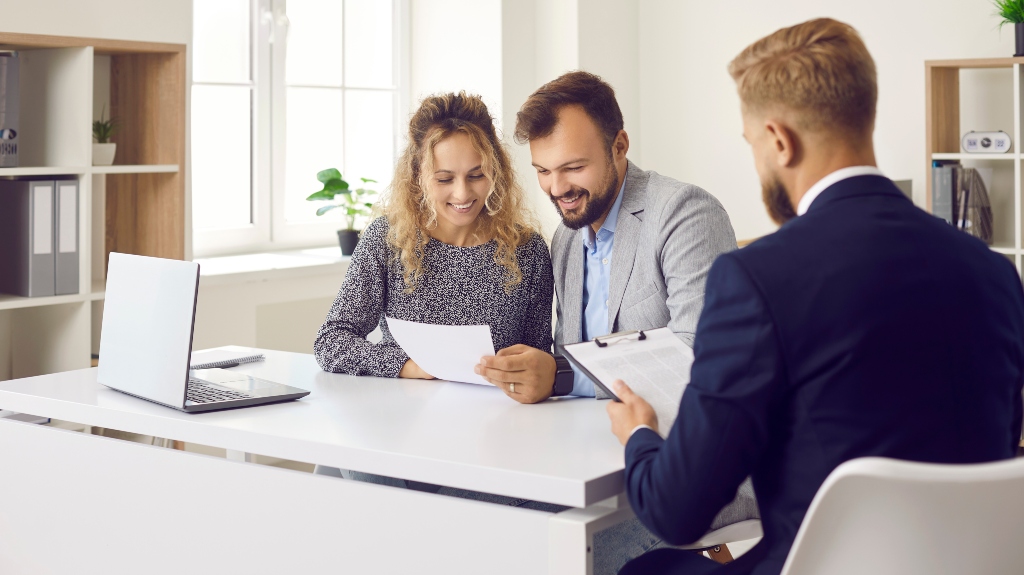 Happy clients sitting at desk in real estate lawyer